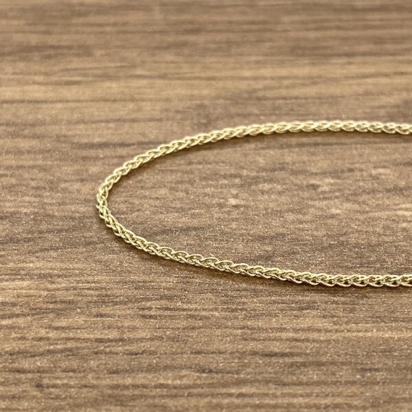A gold chain on a wood surface.