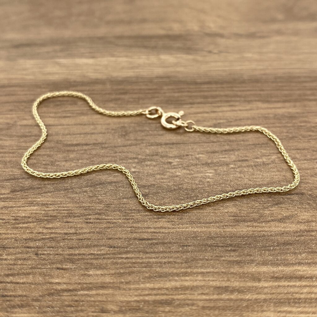 A gold chain on a wood surface.
