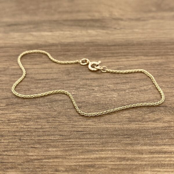 A gold chain on a wood surface.