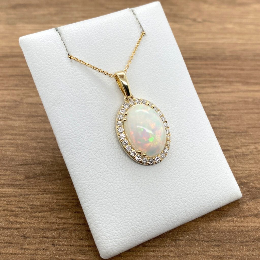 Gold necklace with oval opal and diamond halo.
