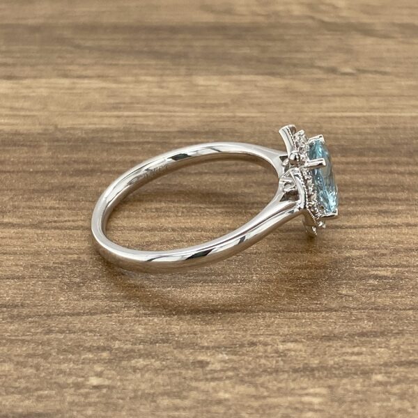 An aquamarine and diamond ring on a wooden table.