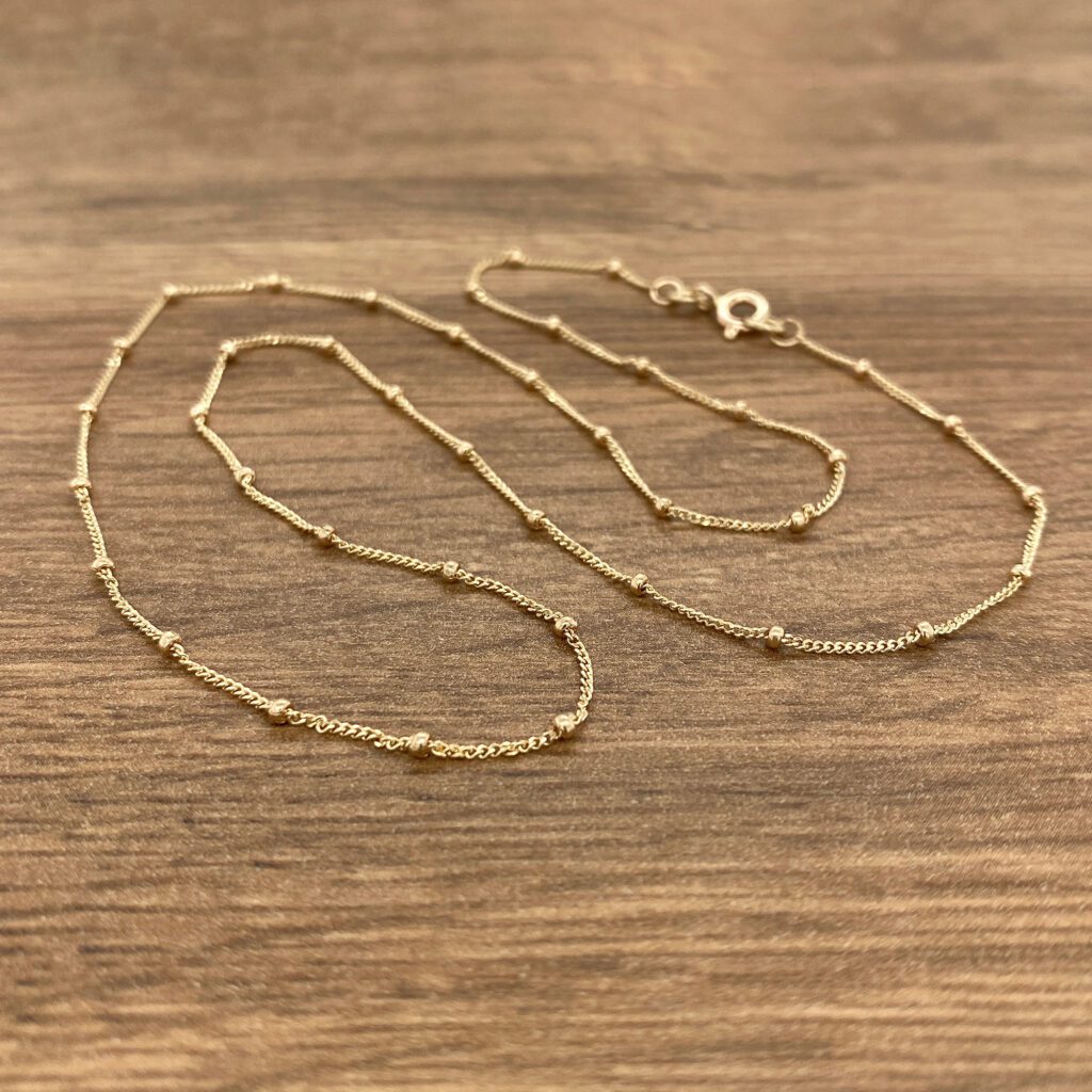 A gold chain with a small bead at the end.
