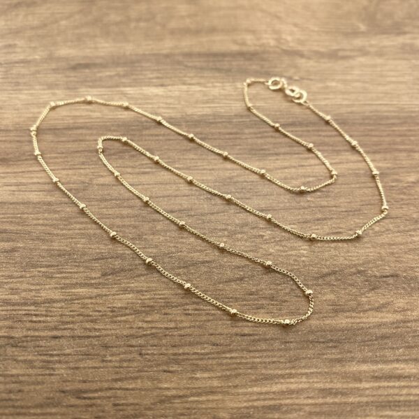 Gold beaded chain necklace on wood