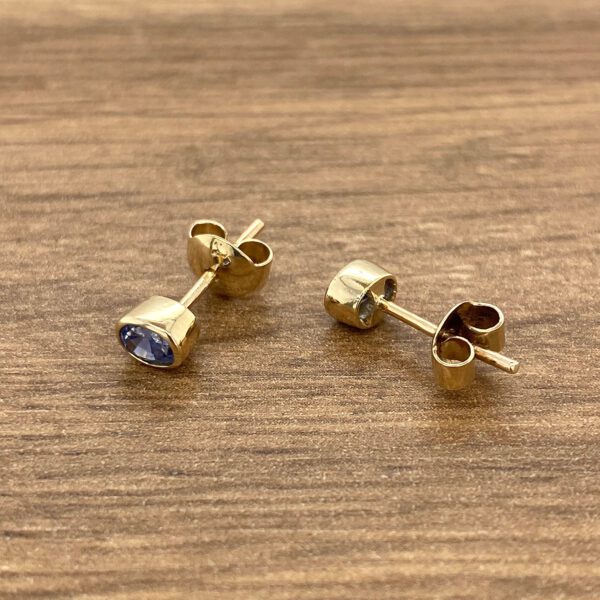 Gold stud earrings with blue gemstones.