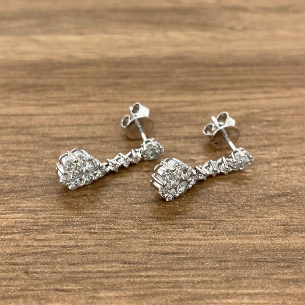 Diamond cluster drop earrings on wood background.