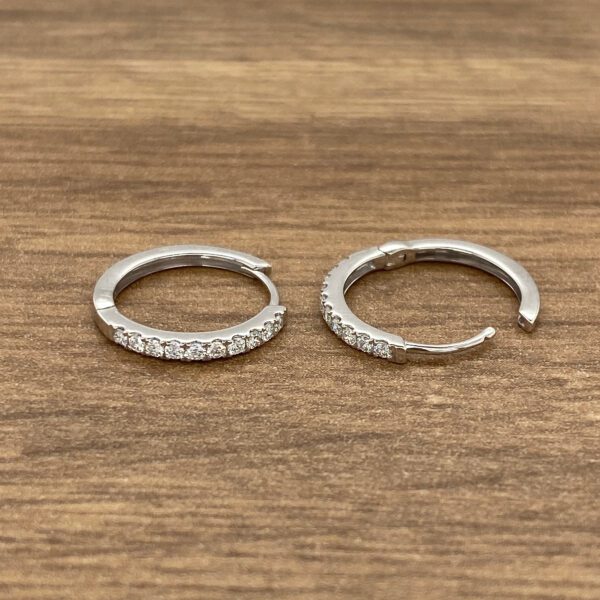 Diamond hoop earrings on a wood background.