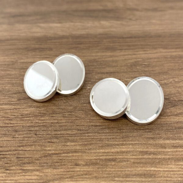 Three silver round buttons on wood.