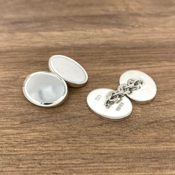 Silver oval cufflinks with chain connector.