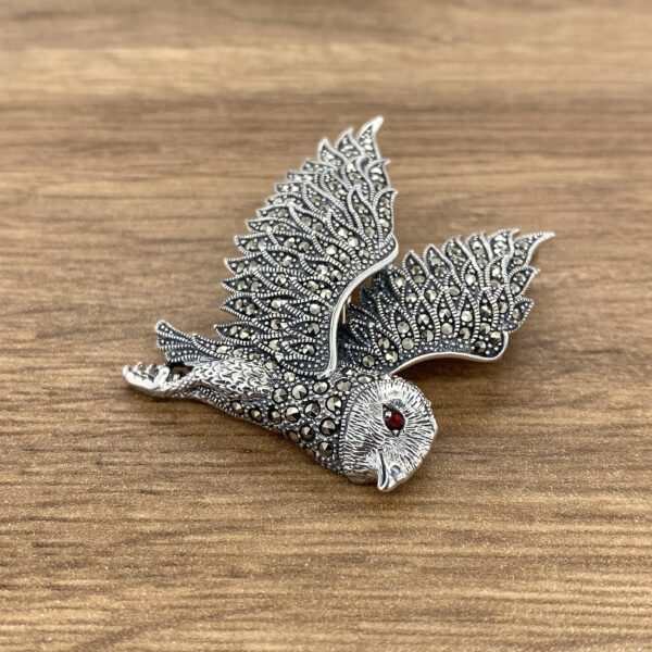 Silver owl brooch with red eye.