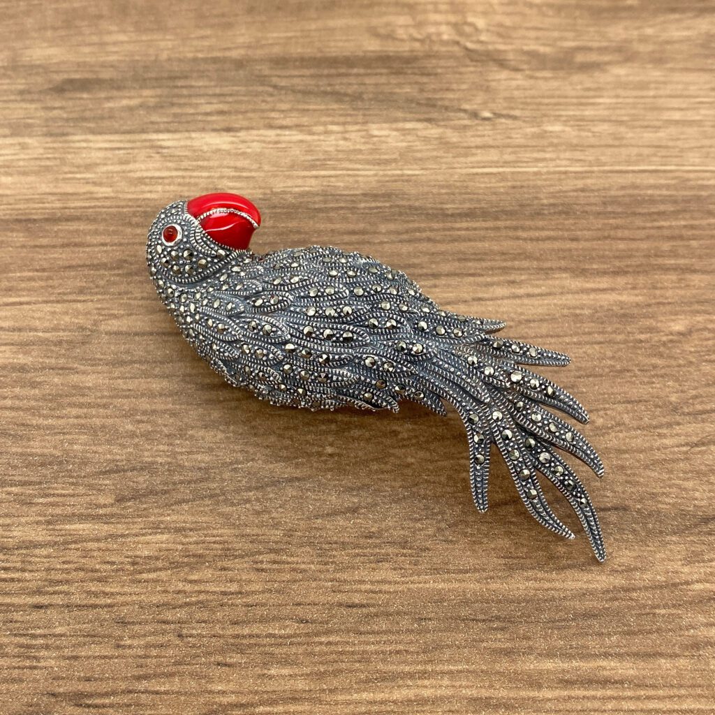 Silver parrot brooch with red beak.