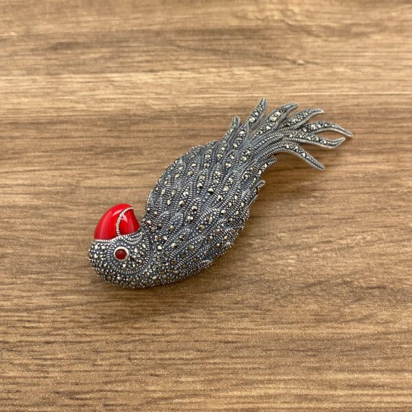 Silver bird brooch with red accents.