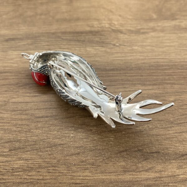 Silver bird brooch with red stone.