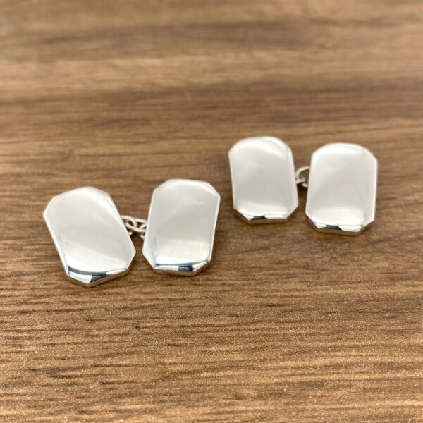 Silver cufflinks on wooden surface.