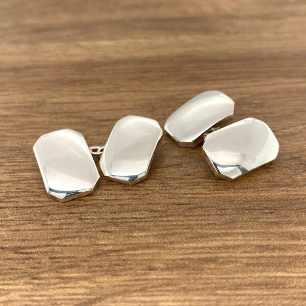 Silver cufflinks on a wooden surface.