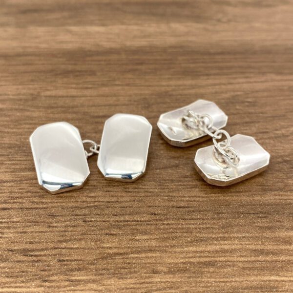 Silver rectangular cufflinks on wood.