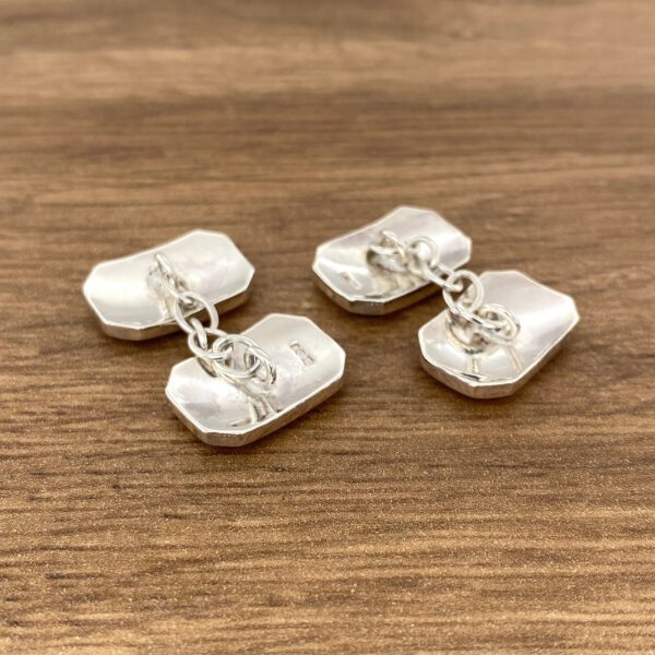 Silver cufflinks on a wooden surface.