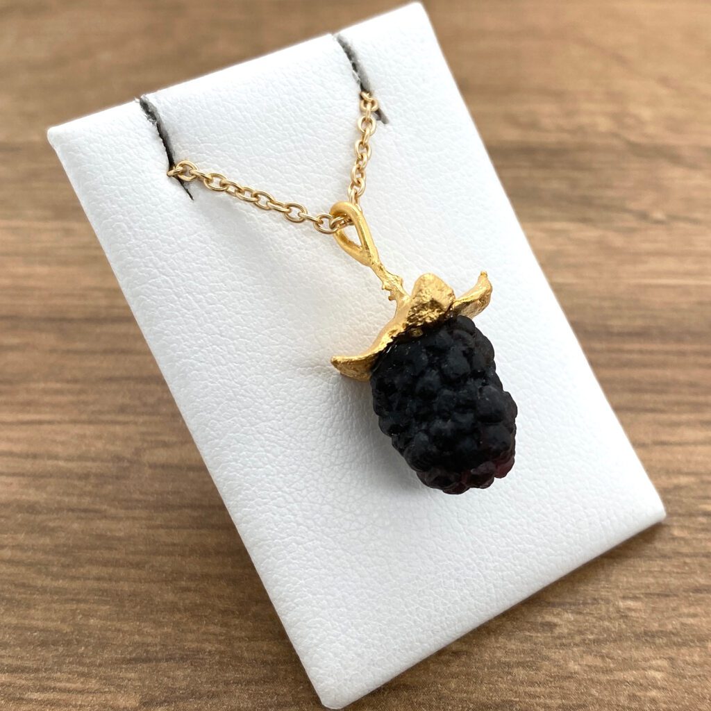 Gold chain necklace with blackberry pendant.