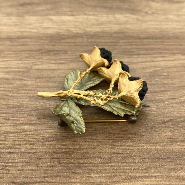 Gold blackberry brooch with green leaves.