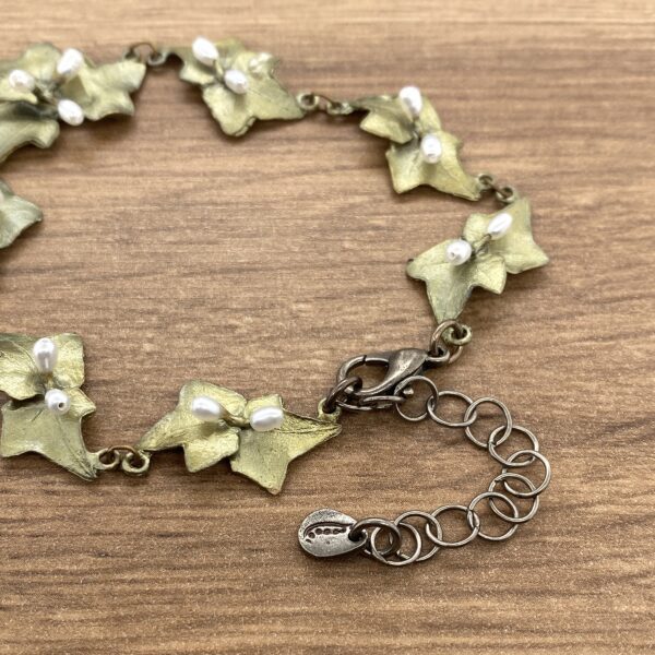 Gold leaf and pearl bracelet on wood.