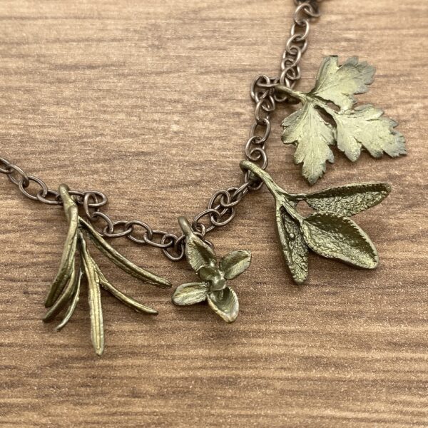 Gold chain necklace with herb charms.