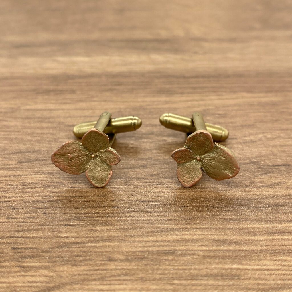 Gold flower-shaped cufflinks on wood.