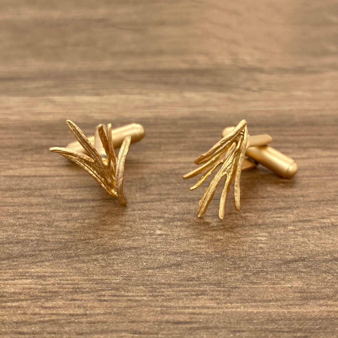 Gold cufflinks with a leaf design.