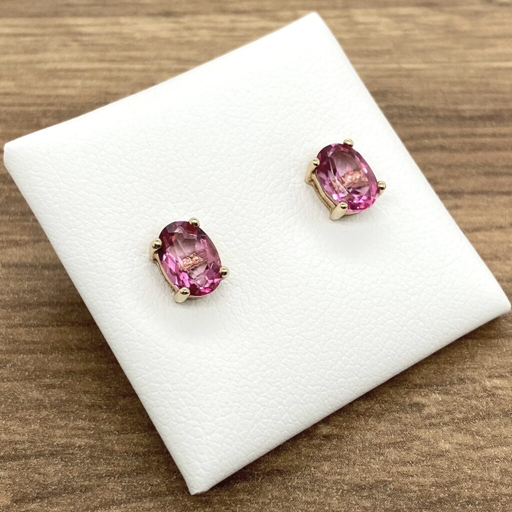 Pink oval gemstone earrings on white display.