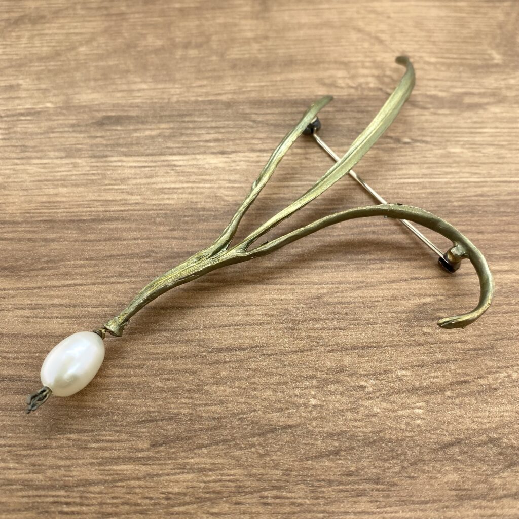 Gold branch brooch with pearl accent.