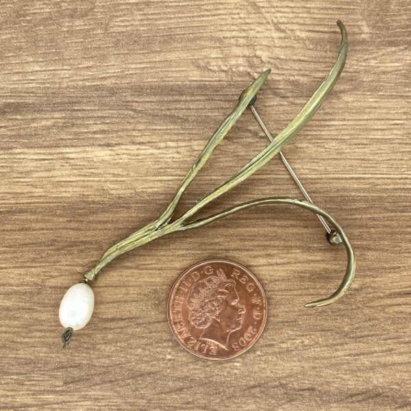 Gold and pearl twig brooch on wood.