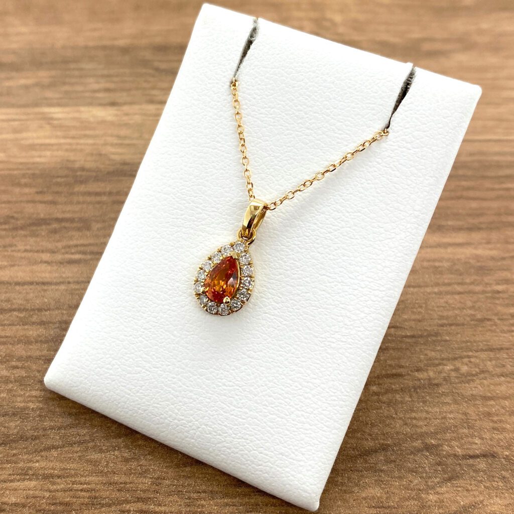 Gold necklace with pear-shaped orange gem.