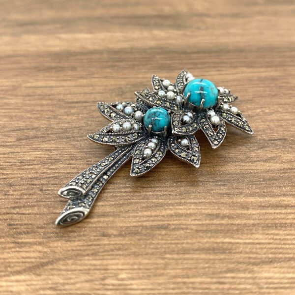 Silver brooch with turquoise stones and pearls.