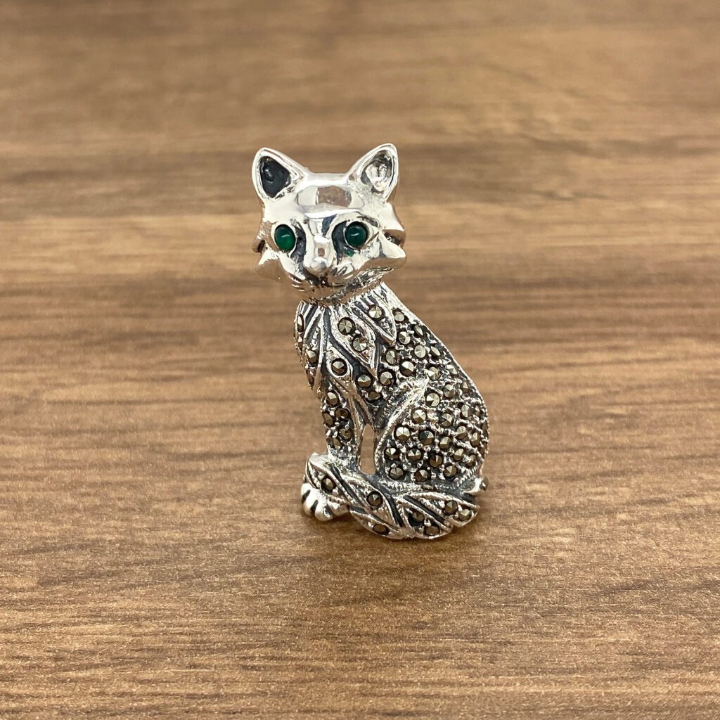 Silver cat brooch with green eyes.