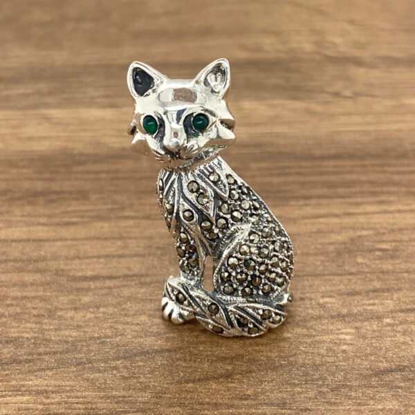 Silver cat brooch with green eyes.
