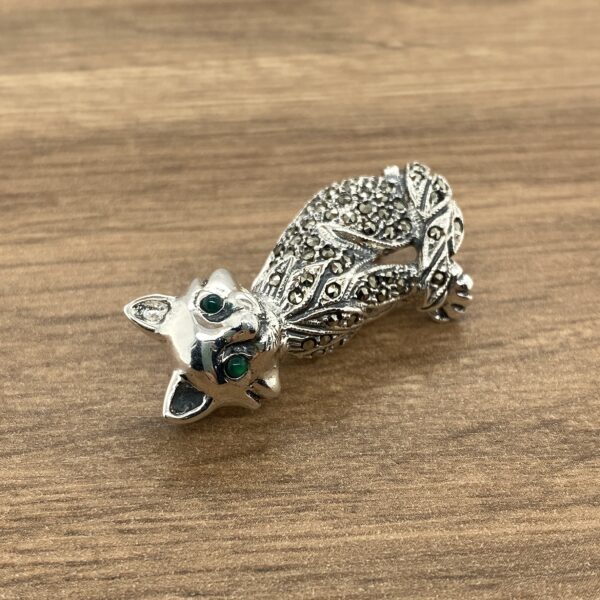 Silver cat brooch with green eyes.