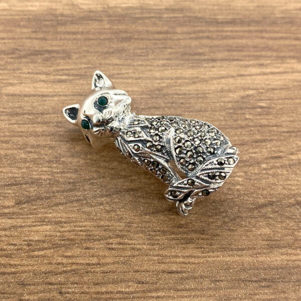 Silver cat brooch with green eyes.