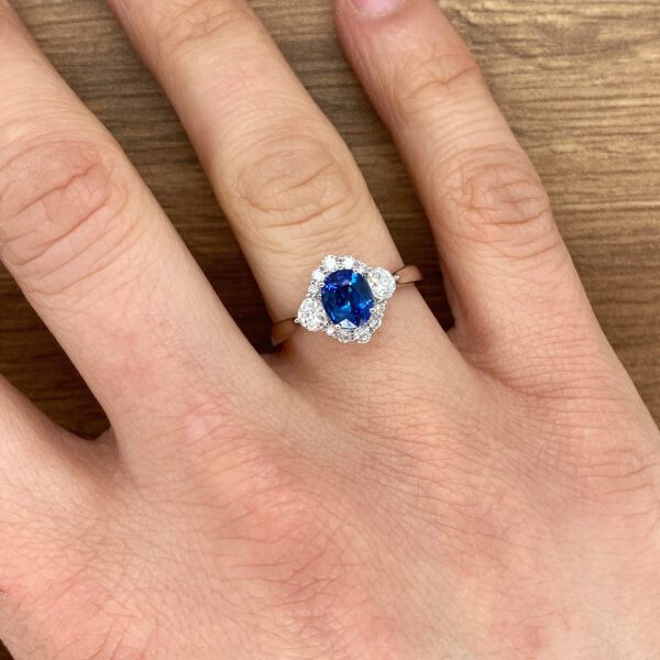 Hand wearing a blue sapphire engagement ring.