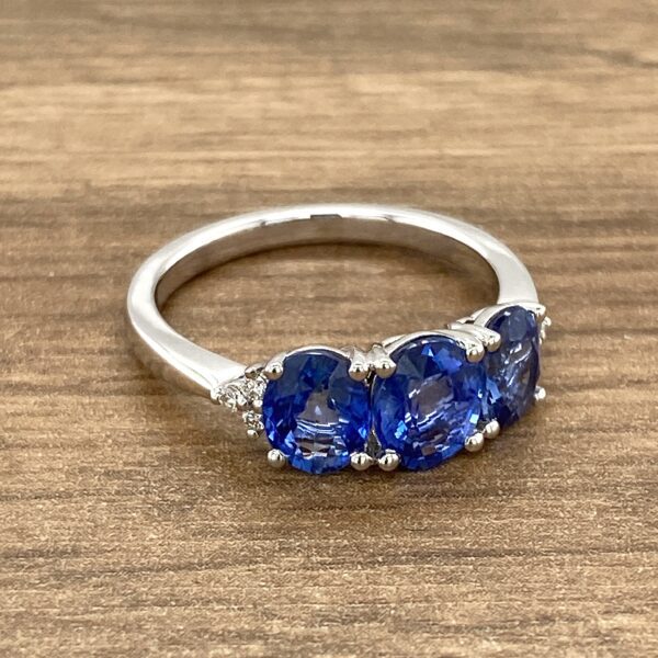 Three sapphire and diamond ring on wood.