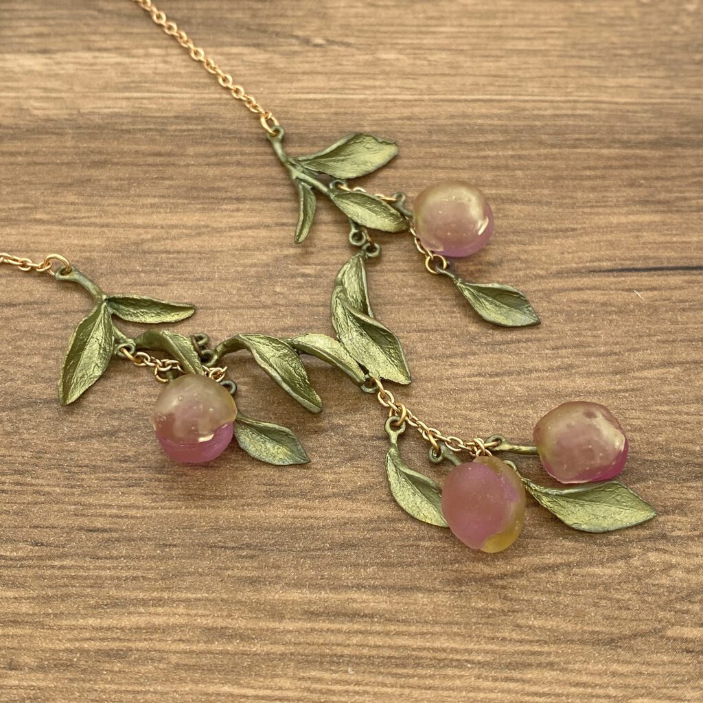 Gold chain necklace with purple fruit and leaves.