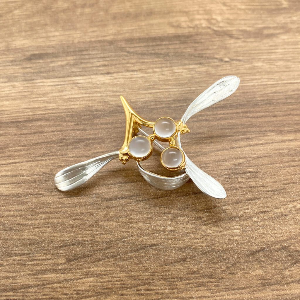Gold and silver brooch with three white stones.