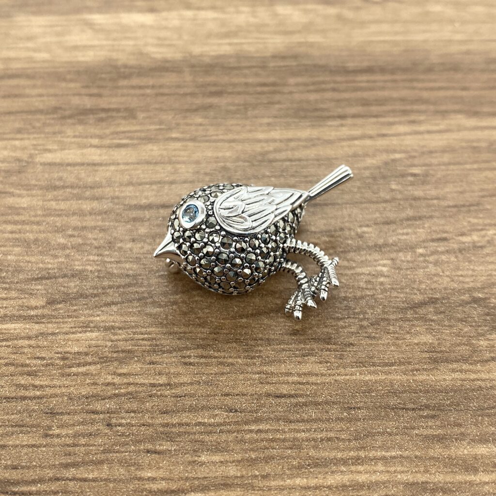 Silver bird brooch with blue eye.