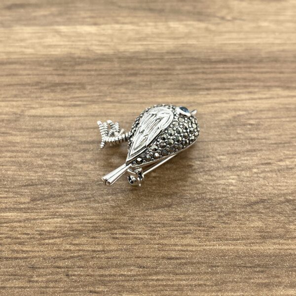Silver bird brooch with blue eye.