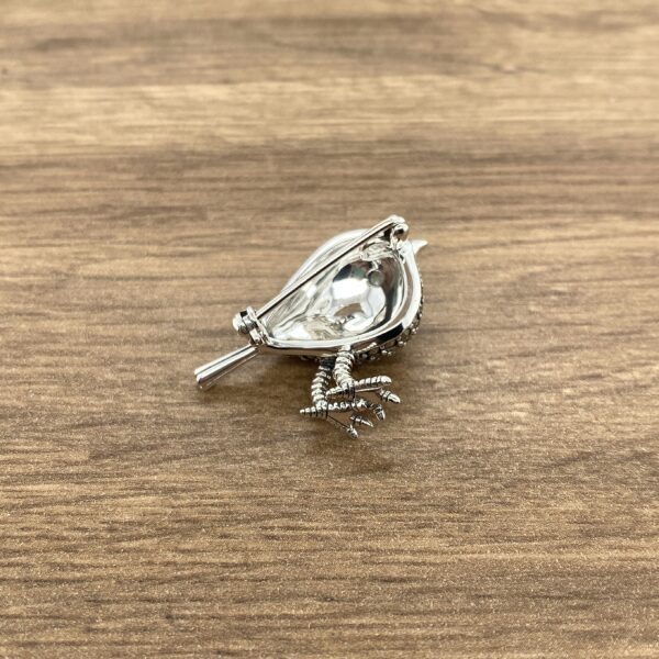 Silver bird brooch with detailed feet.