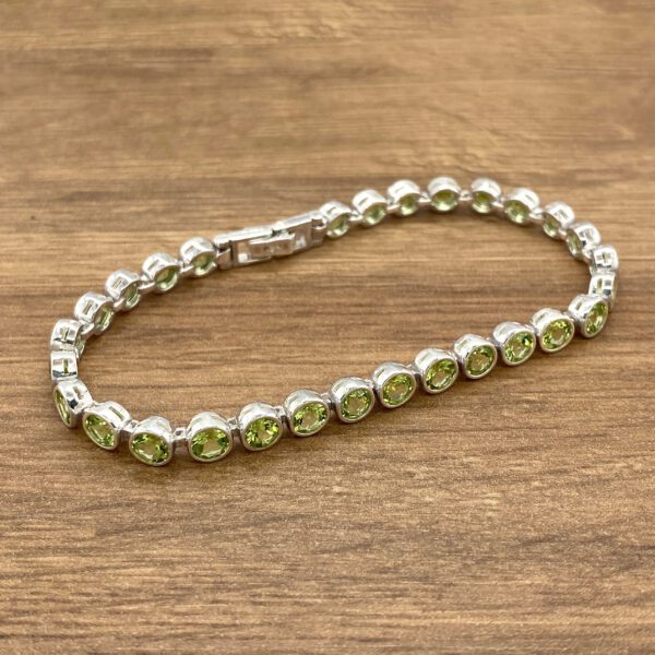 Silver peridot tennis bracelet on wood.