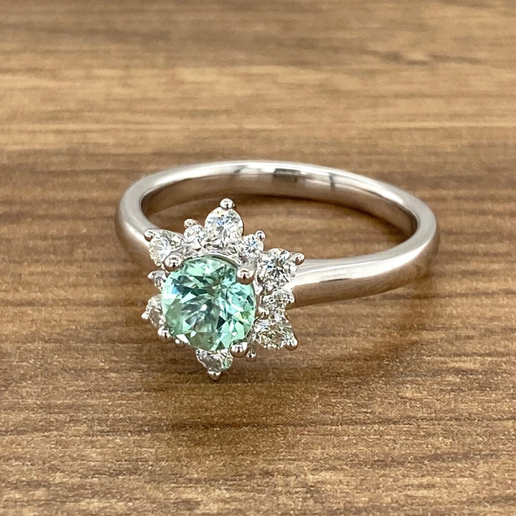 Green gemstone ring with diamond halo.