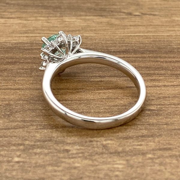 Green gemstone ring with halo setting.