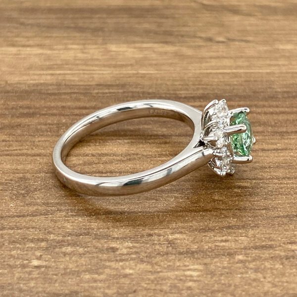Green gemstone ring with halo setting.