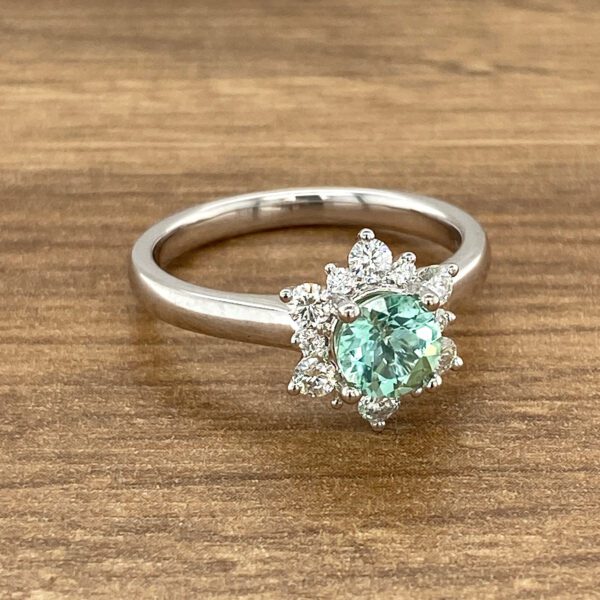 Green gemstone ring with diamond halo.