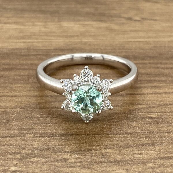 Green gemstone ring with diamond halo.