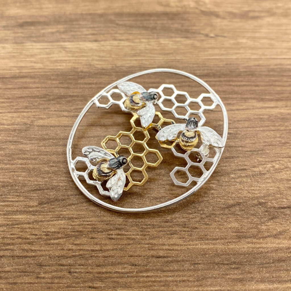 Silver bee brooch with honeycomb design.