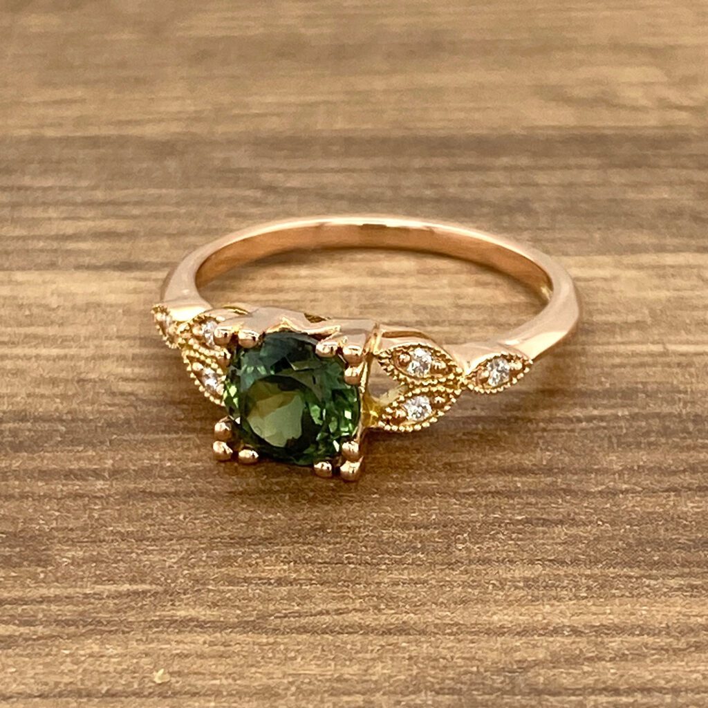 Rose gold ring with green gemstone.
